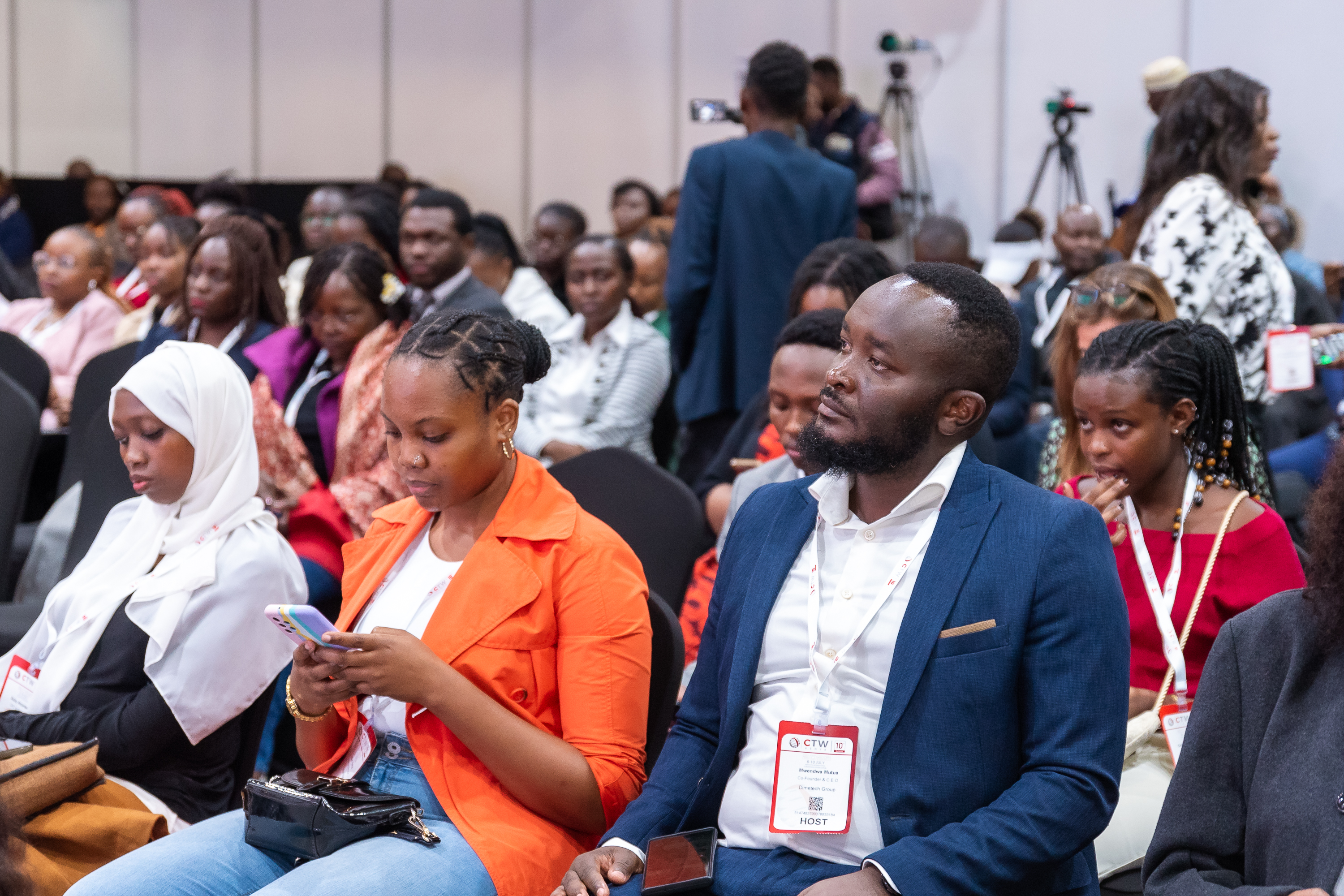 Attendees seated in the audience, some using their phones