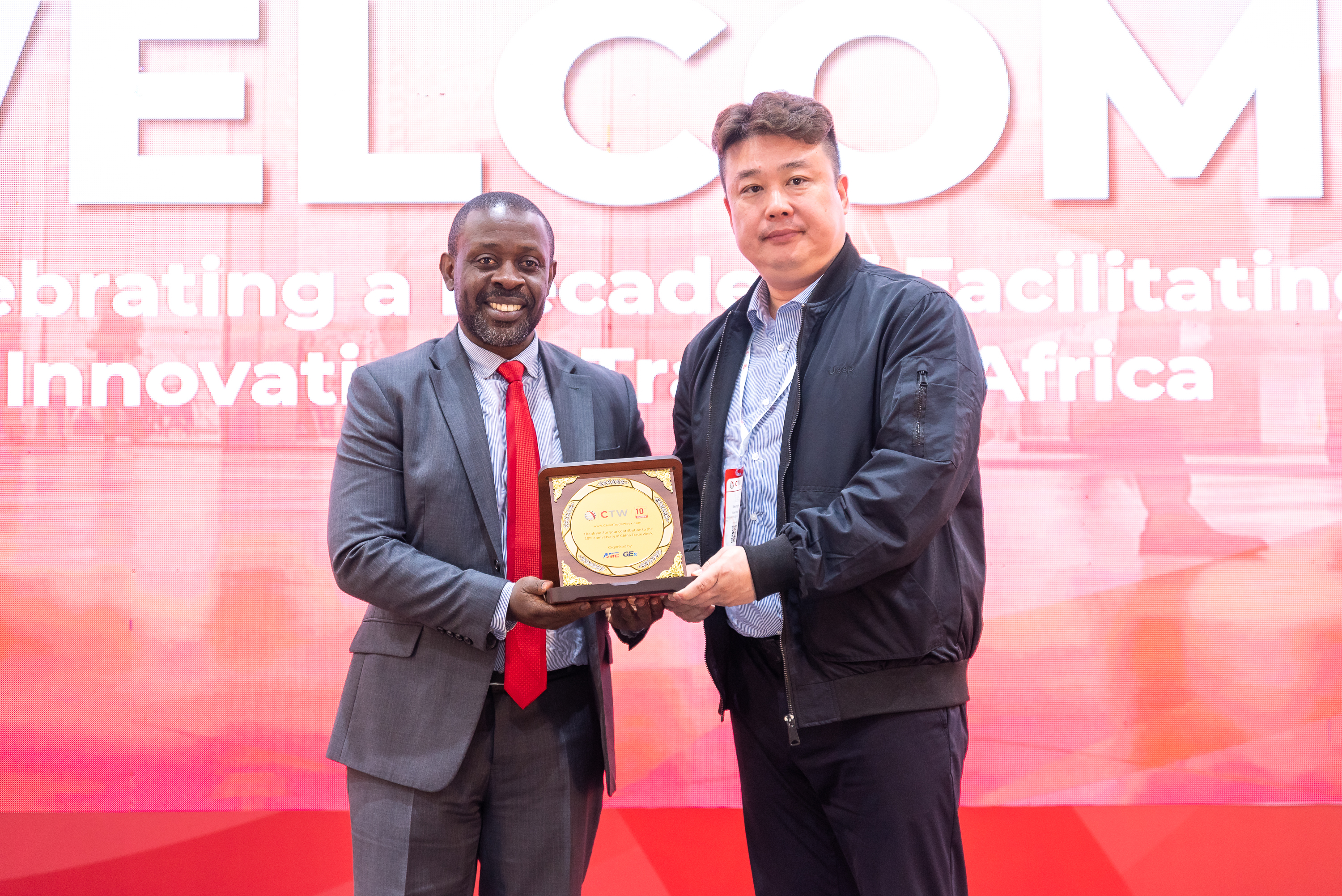 Two men holding a plaque on stage
