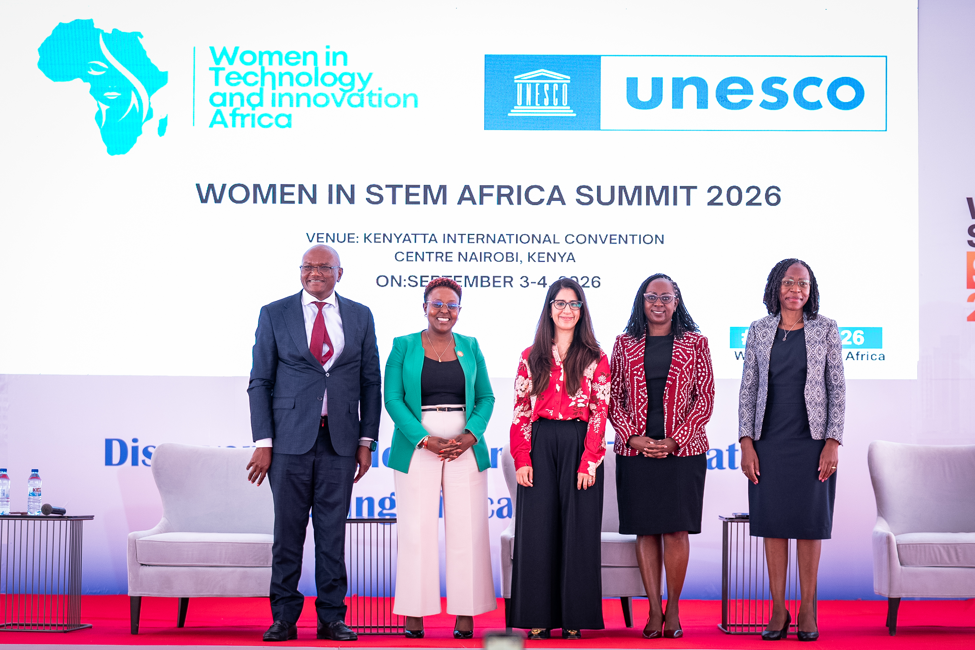Speakers standing together on stage in front of the summit backdrop