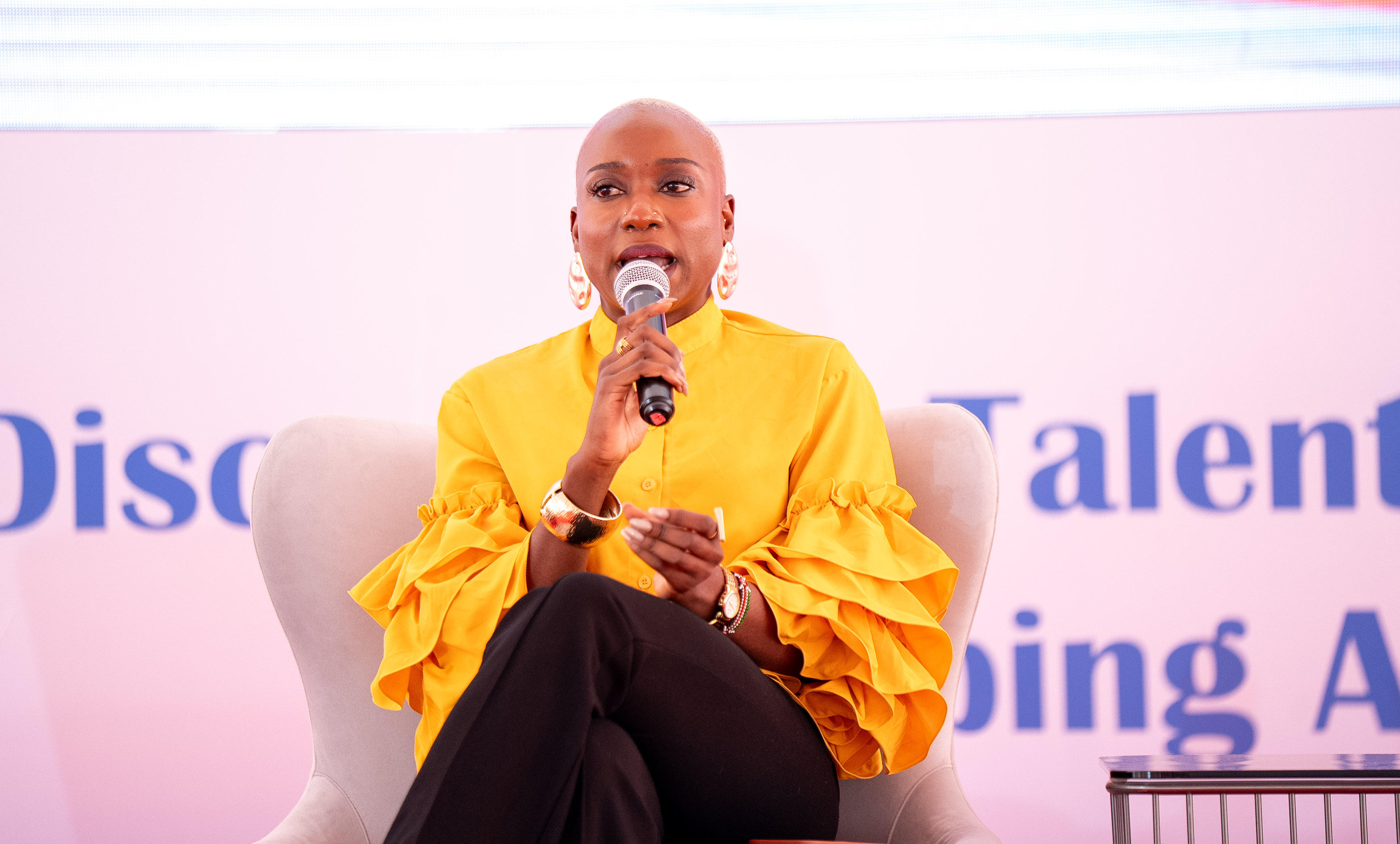 A speaker in yellow addressing the audience from the stage