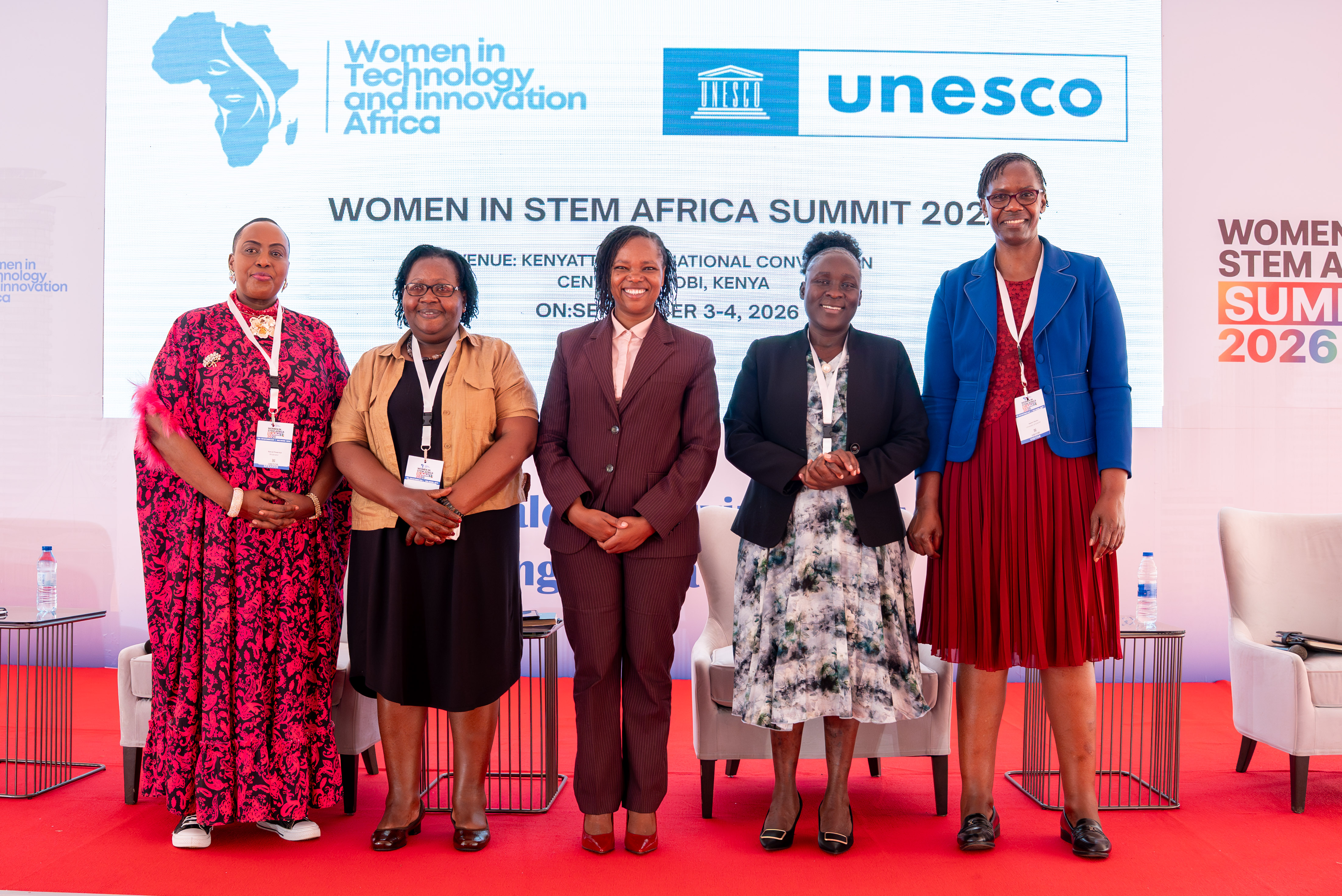 Five women speakers standing together on stage in front of the summit backdrop